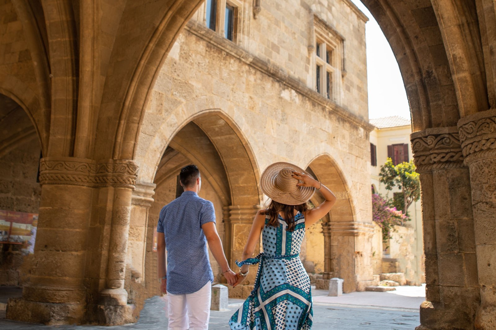 a man and woman holding hands and walking in an archway