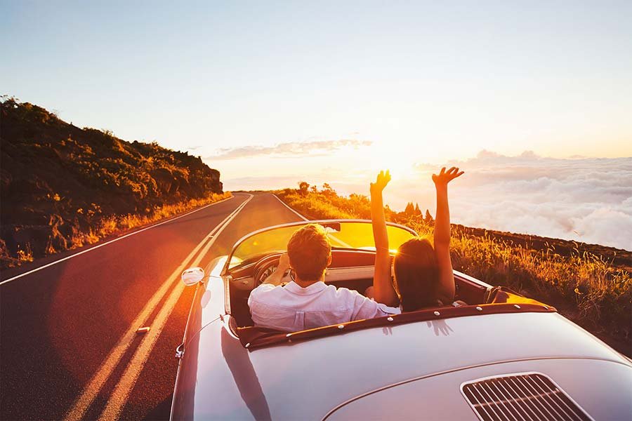 a couple driving a car in sunset