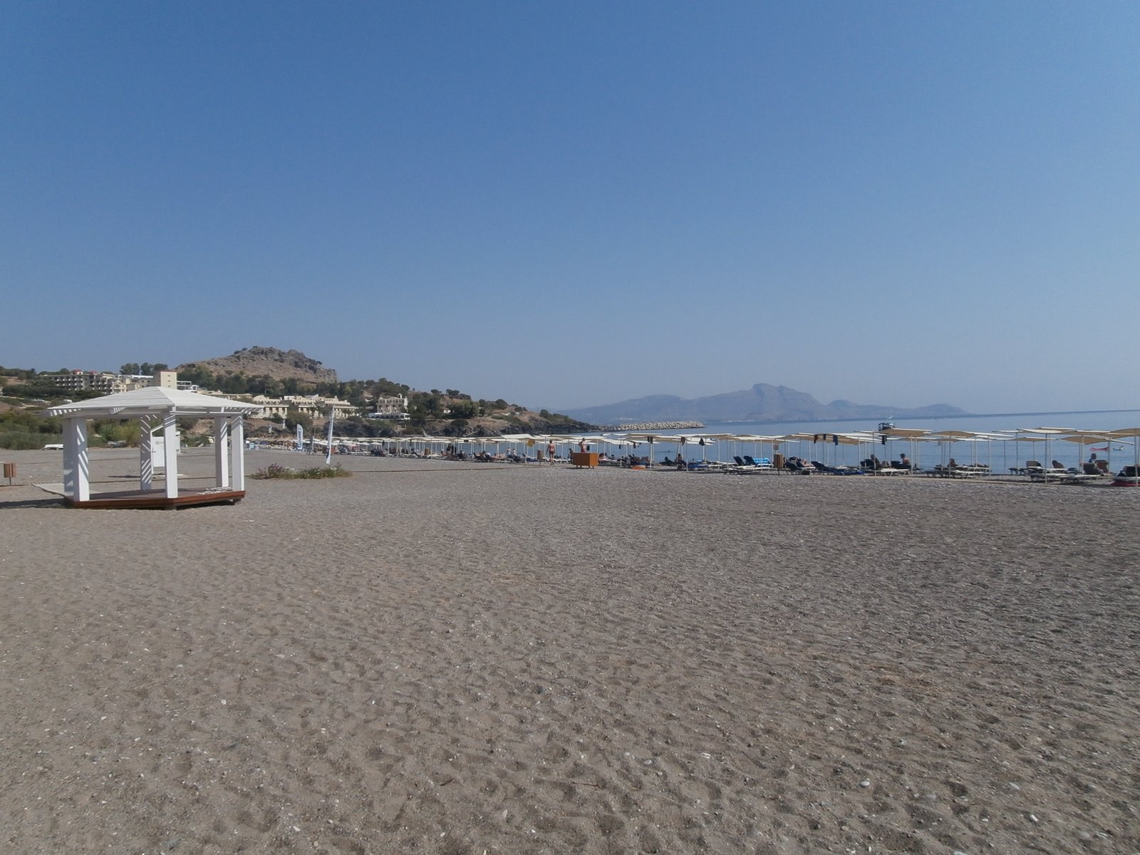 Pebble shore and sunbeds along Vlycha Beach in Rhodes
