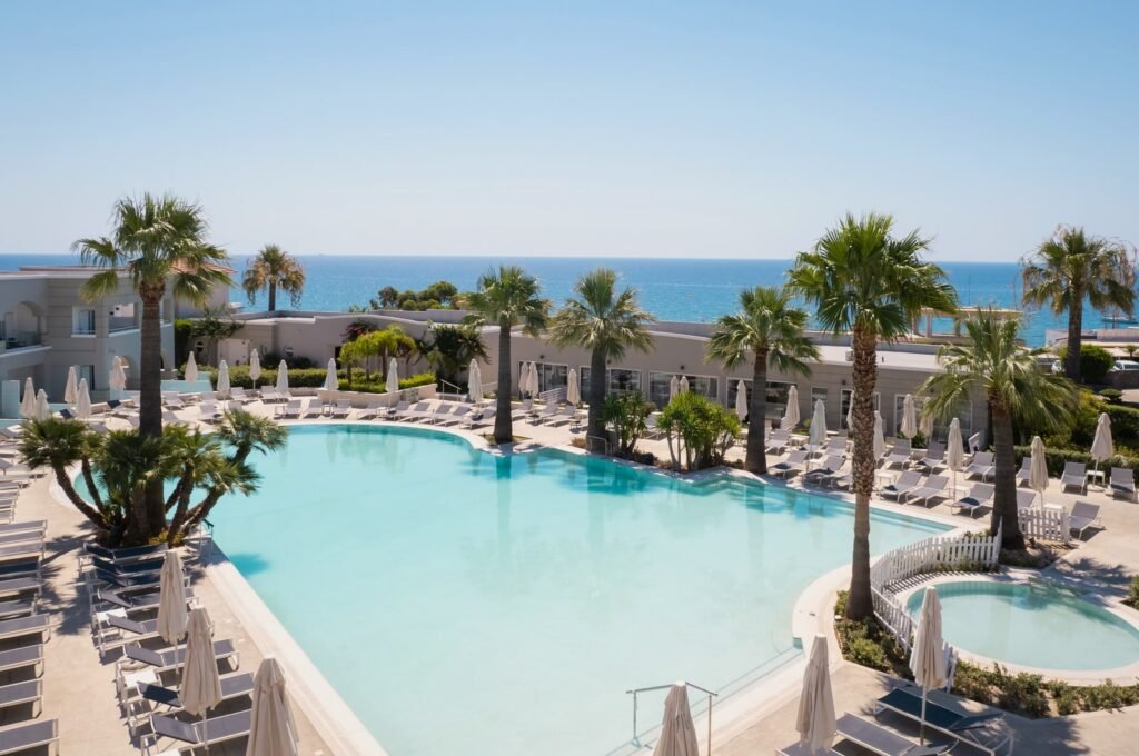 Main pool, palm trees and sea view at Mitsis Rodos Village in Kiotari, Rhodes